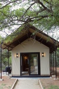 a small white building with a large door under a tree at Mkhuze Trails Lodge in Hluhluwe