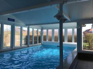 a large indoor swimming pool with blue water at Ferienwohnung Auszeit Erika 1 in Burhave