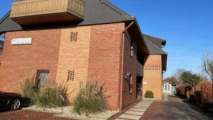 a red brick building with a black roof at Ferienwohnung Auszeit Erika 1 in Burhave