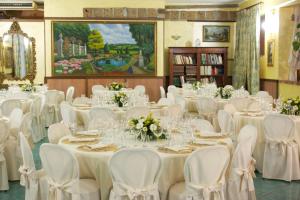 un salón de banquetes con mesas y sillas blancas y una pintura en Hotel Antico Residence Roma, en Monterosi