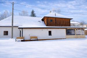 a house with snow on the roof and two benches at Chalupa Herbortice in Cotkytle