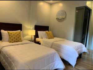 a bedroom with two beds with white sheets and yellow pillows at OYO 1177 The Great Molave in Tagaytay