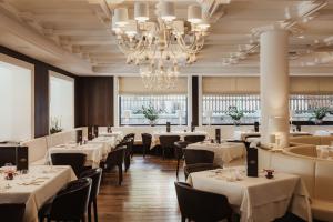 a restaurant with white tables and chairs and a chandelier at Hotel Genziana in Ortisei