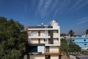 a tall white building with trees in front of it at hotel NemiResidency in Jagdalpur