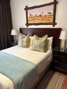 a bedroom with a bed with two lamps and a painting on the wall at Alendo Apartments in Johannesburg +51 photos