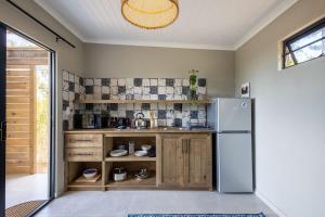 a kitchen with a refrigerator and wooden cabinets at Myrtle Forest Retreat Cabin in Plettenberg Bay +10 photos