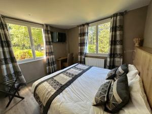 a bedroom with a bed and two windows at Logis Hôtel Beau Site in Loubaresse +48 photos