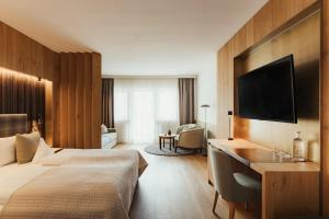 a hotel room with a bed and a desk and a television at Hotel Genziana in Ortisei