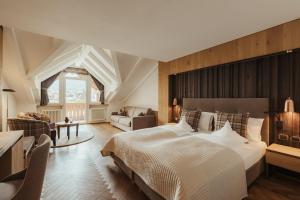 a bedroom with a large bed and a living room at Hotel Genziana in Ortisei +67 photos