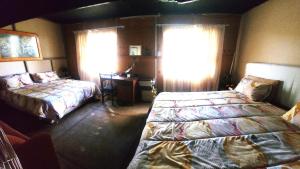 a bedroom with two beds and a table and windows at Buffelslaagte at the Vaal in Oranjeville