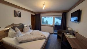 a hotel room with a bed and a television at Gästehaus Bergland in Berwang