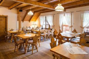 a restaurant with wooden tables and chairs and windows at Cabana Plaiul Foii in Zărneşti