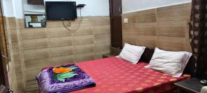 a small room with a bed with a red blanket at Hotel Utsav in Khatīma