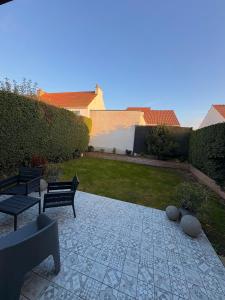 a patio with two benches and a yard with grass at Maison moderne entre terre et mer in Coquelles