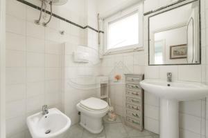 a white bathroom with a toilet and a sink at Casa Malu in Marina di Campo +12 photos