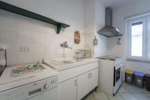 a white kitchen with a sink and a stove at Casa Malu in Marina di Campo