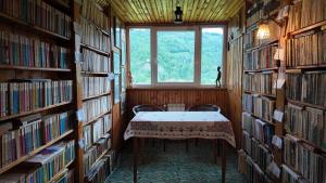 a library with a table and chairs in a room with books at Casa Santa Maria Bran in Moieciu de Jos