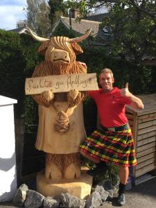 a man standing next to a statue of a cow at Ardlogie Guest House in Aviemore