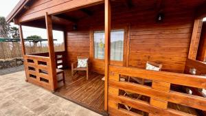 a wooden cabin with two chairs on a deck at Betenama - Rustic Hideaway with Pool & Garden in Tesbabo