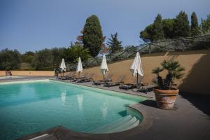 a swimming pool with chairs and umbrellas at Borgo di Colleoli Resort in Colleoli