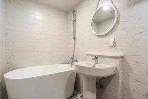a white bathroom with a bath tub and a sink at 엘루이호텔 in Busan