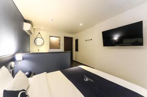 a bedroom with a bed and a flat screen tv at 엘루이호텔 in Busan +4 photos