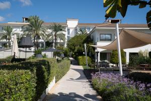 a walkway in front of a building with trees and bushes at Prinsotel La Dorada & Spa in Playa de Muro