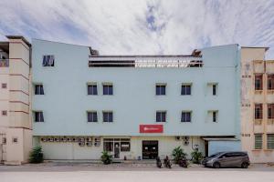 a white building with cars parked in front of it at RedDoorz near Soekarno Hatta Airport 3 in Tangerang