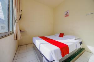 a small room with a bed with a red blanket at RedDoorz near Soekarno Hatta Airport 3 in Tangerang