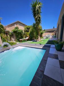 a swimming pool in a yard with a palm tree at Zufike Self Catering in Port Elizabeth