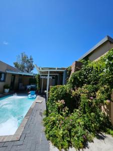 a swimming pool with plants next to a house at Zufike Self Catering in Port Elizabeth
