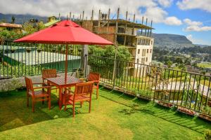 a table and chairs with a red umbrella on a balcony at Highland Stonehouse in Nuwara Eliya