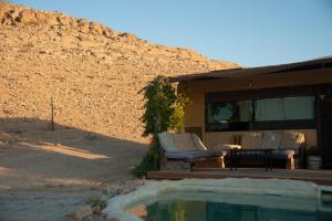 a house with a swimming pool next to a wall at אוטובוס בכרם in Mitzpe Ramon