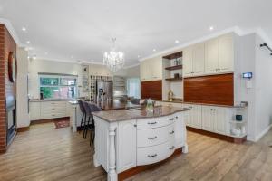 a kitchen with white cabinets and a large island at Manor On Main in Midrand