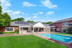 a home with a pool and a house with solar panels on the roof at Manor On Main in Midrand