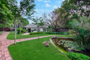 a garden with a pond and a house at Manor On Main in Midrand
