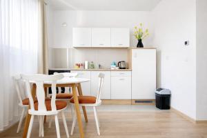 a kitchen with white cabinets and a table and chairs at Apartmani Sun & Moon in Žepče
