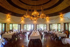 a dining room with white tables and chairs and chandeliers at Lake Manyara Serena Safari Lodge in Karatu