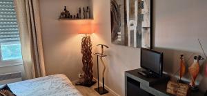 a bedroom with a lamp and a tv in a room at CYBELE APARTMENT - HYPER CENTRE in Arcachon
