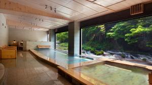 a large swimming pool in a house with a large aquarium at Aizu Higashiyama Onsen "Shosuke no Yado Takinoyu" since1880 in Aizuwakamatsu