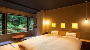 a bedroom with a large white bed and a window at Aizu Higashiyama Onsen "Shosuke no Yado Takinoyu" since1880 in Aizuwakamatsu +175 photos