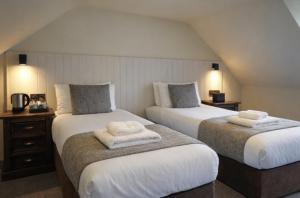 two beds in a hotel room with towels on them at The Whisky Vaults in Oban