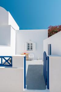 a white house with a blue gate and a table at Coastal Escape - 2 min from Perissa Beach in Perissa