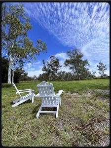 two white rocking chairs sitting in a field at Outback Getaway Home in Mount Isa