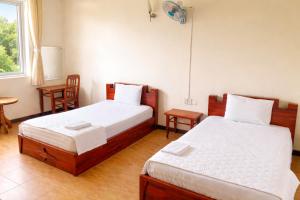 a bedroom with two beds and a table and a window at Candy Hotel Can Tho in Cái Răng