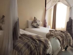 a bedroom with two beds and a window at 1688 BB7 Suites in Victoria Falls