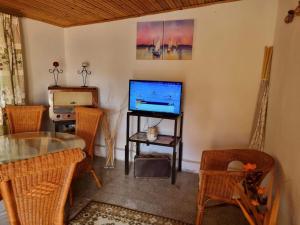 a living room with a tv and a table and chairs at Muskátlis Ház in Balatonlelle