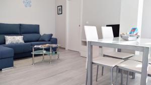 a living room with a blue couch and a table and chairs at Apartamentos los Acantilados Nº 1 Cobreces in Cóbreces