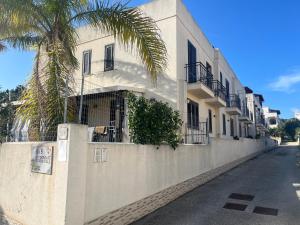 a white building with a palm tree next to a street at B&B Agrodolce in San Vito lo Capo