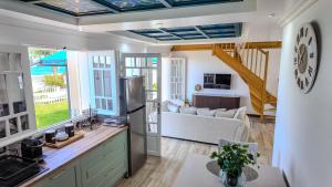 a kitchen and living room with a couch and a clock at La Villa Bleue, Pieds dans l'eau in Saint-Leu